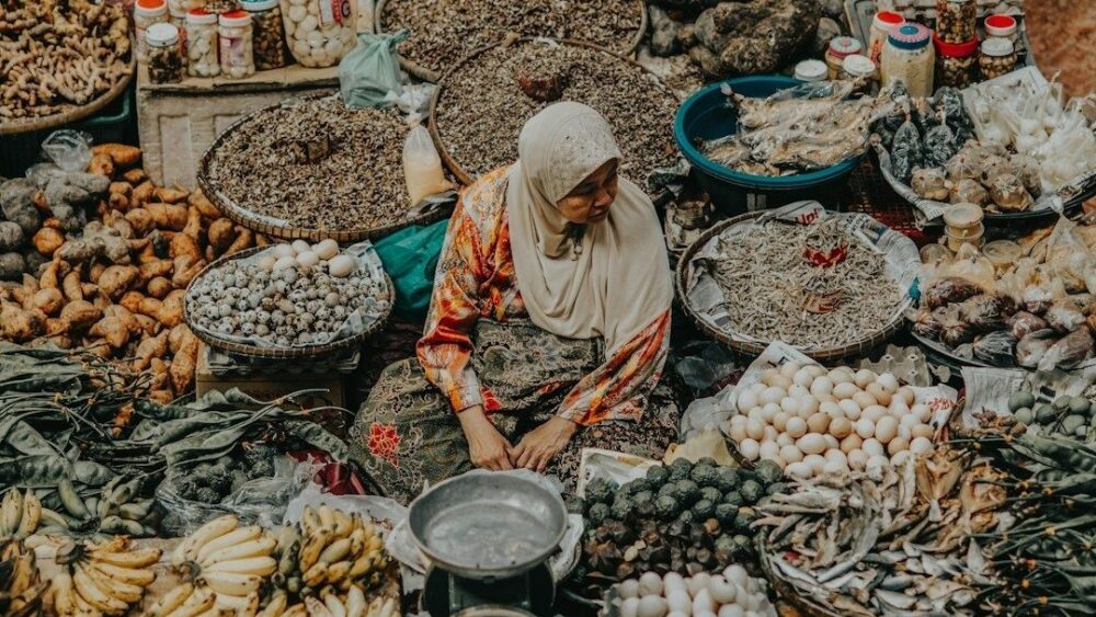 Vendedora sentada entre alimentos variados en un mercado local