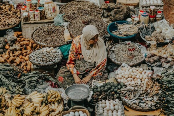 Vendedora sentada entre alimentos variados en un mercado local